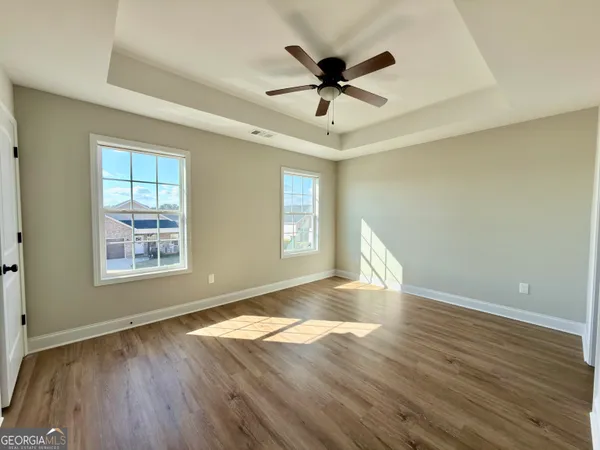 a view of empty room with wooden floor and fan