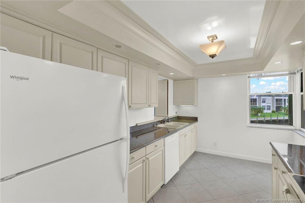 1950 Southwest Palm City Road, Unit 14207 Stuart, FL 34994 - Photo 18 of 50 a kitchen with stainless steel appliances granite countertop a refrigerator a sink a stove and white cabinets