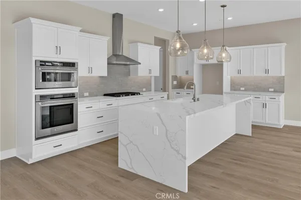 a kitchen with stainless steel appliances kitchen island granite countertop a sink a stove and a wooden floors
