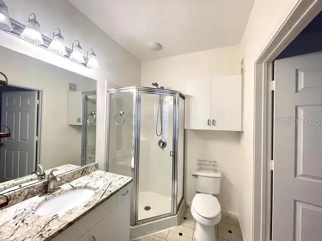 a bathroom with a granite countertop sink toilet mirror and shower