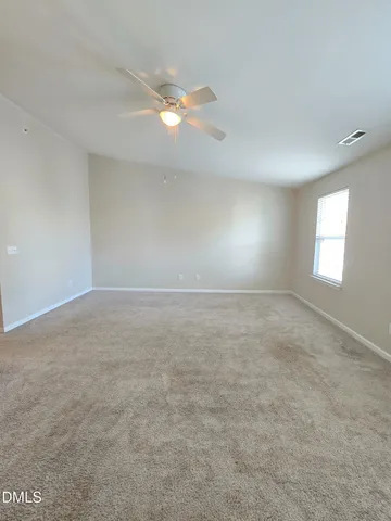 a view of an empty room with a chandelier fan