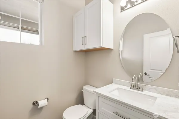 a bathroom with a toilet sink vanity and mirror