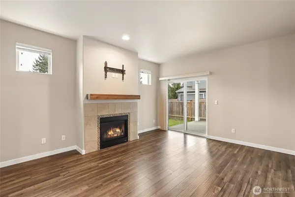 a view of an empty room with wooden floor fireplace and a window