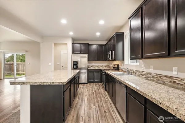 a large kitchen with stainless steel appliances granite countertop a sink stove and refrigerator