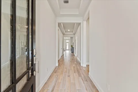 a view of a hallway with wooden floor and a bathroom