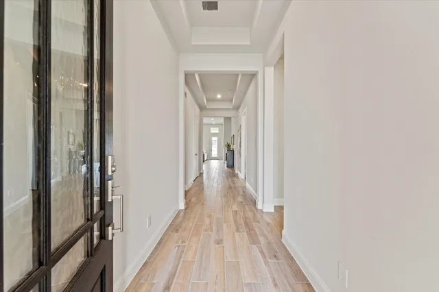 a view of a hallway with wooden floor and a bathroom