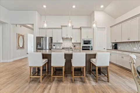 a kitchen with stainless steel appliances granite countertop a dining table chairs refrigerator and cabinets
