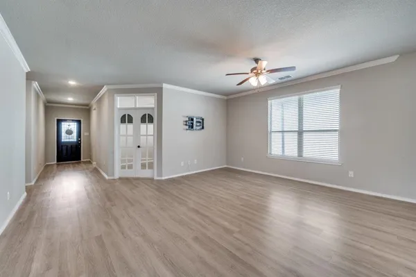 a view of empty room with wooden floor and fan