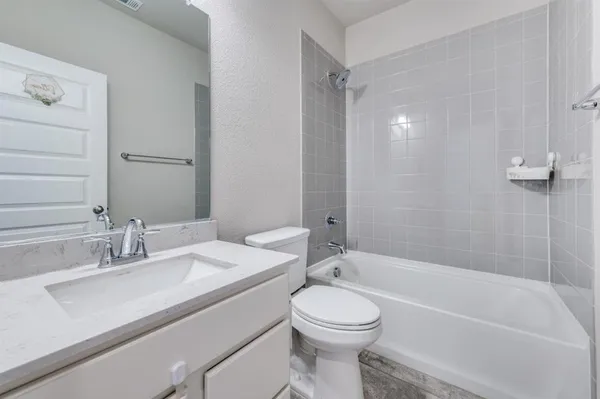 a bathroom with a bathtub shower sink vanity mirror and toilet