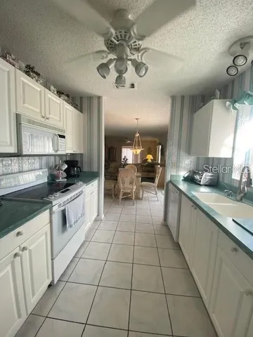 a large white kitchen with cabinets a sink a stove a dining table and chairs