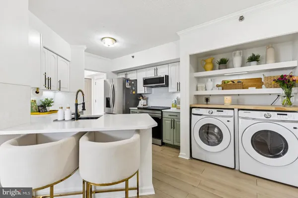 a kitchen with kitchen island a stove a sink a refrigerator and white cabinets with wooden floor