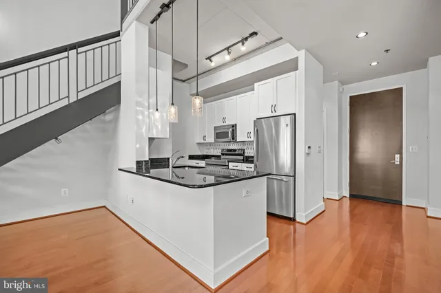 a kitchen with stainless steel appliances granite countertop a refrigerator a stove and a wooden floors