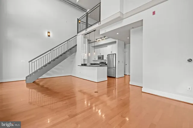 a view of empty room with wooden floor and kitchen view