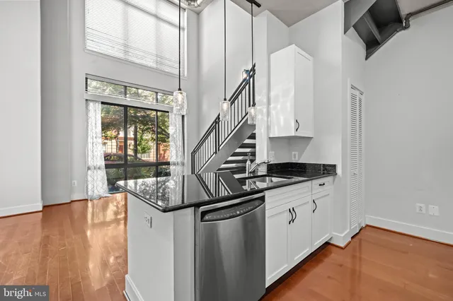 a kitchen with stainless steel appliances granite countertop a sink a stove and a wooden floors