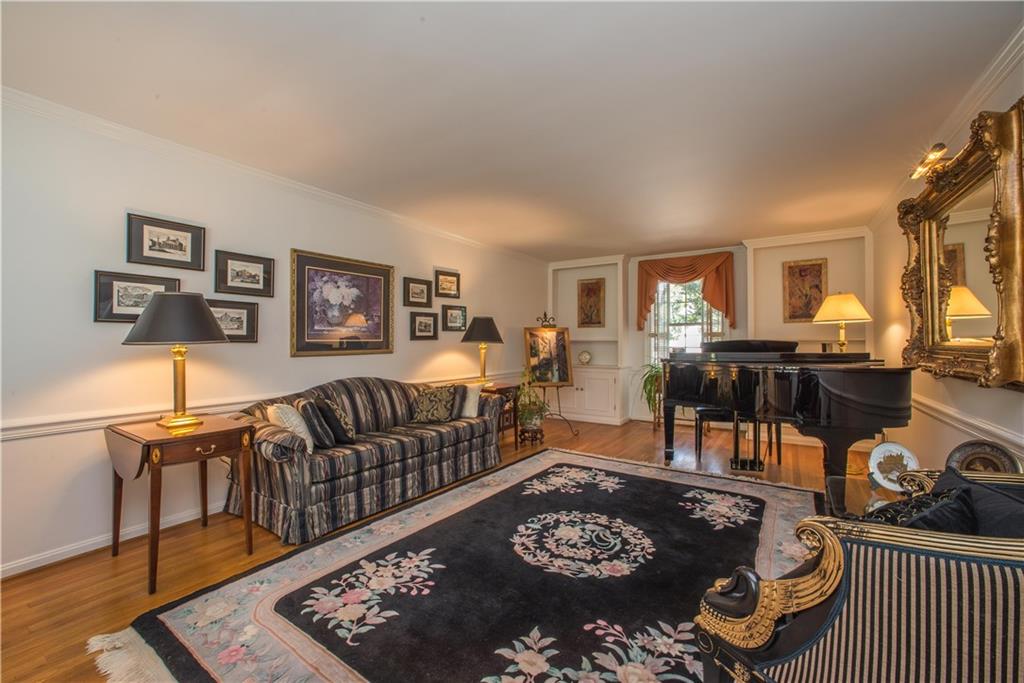 Oak hardwood flooring, chair rail and crown molding trim are found in the luxuriously sized living room (measuring 24X13).  This view shows built-ins and a window that overlooks the rear lawn. 
