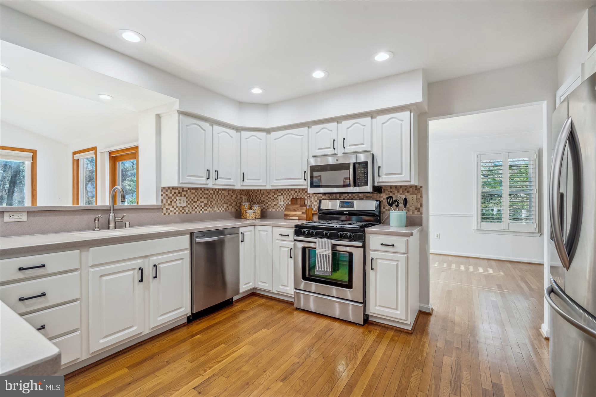 4048 Arjay Circle Ellicott City, MD 21042 - Photo 9 of 56 a kitchen with stainless steel appliances granite countertop a stove top oven a sink and white cabinets with wooden floor
