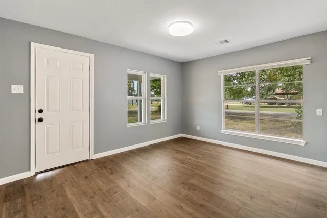 an empty room with wooden floor and windows