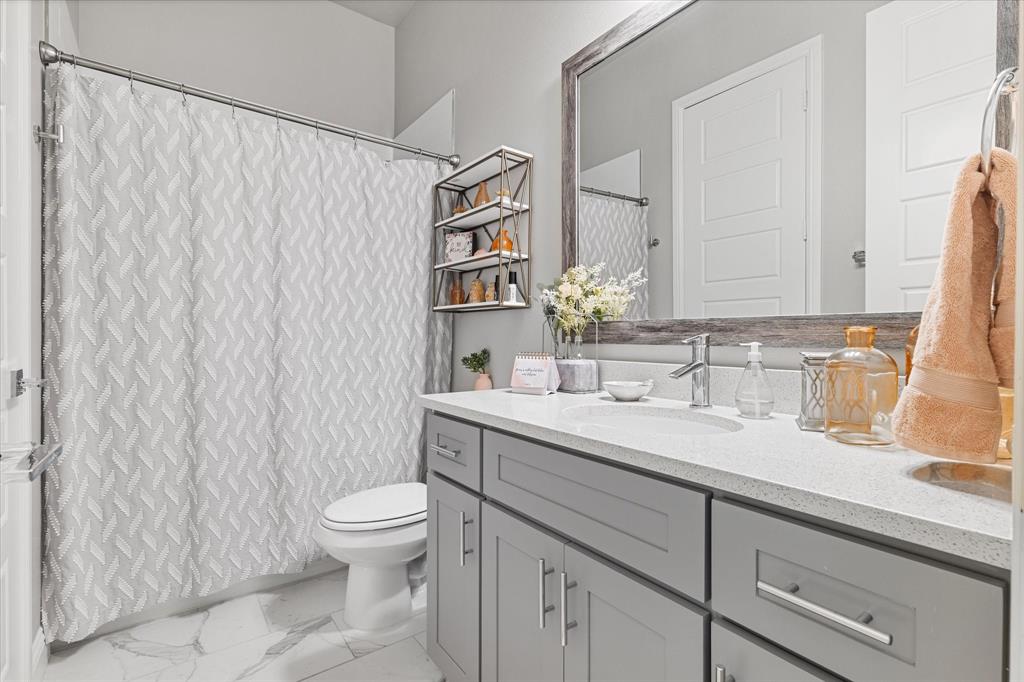 6013 Page Street Frisco, TX 75034 - Photo 15 of 38 a bathroom with a granite countertop sink a toilet and a mirror