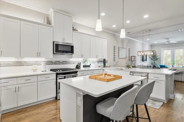 a kitchen with a sink a stove a refrigerator and white cabinets with wooden floor