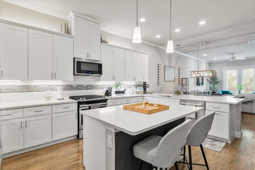 6013 Page Street Frisco, TX 75034 - Photo 16 of 38 a kitchen with a sink a stove a refrigerator and white cabinets with wooden floor