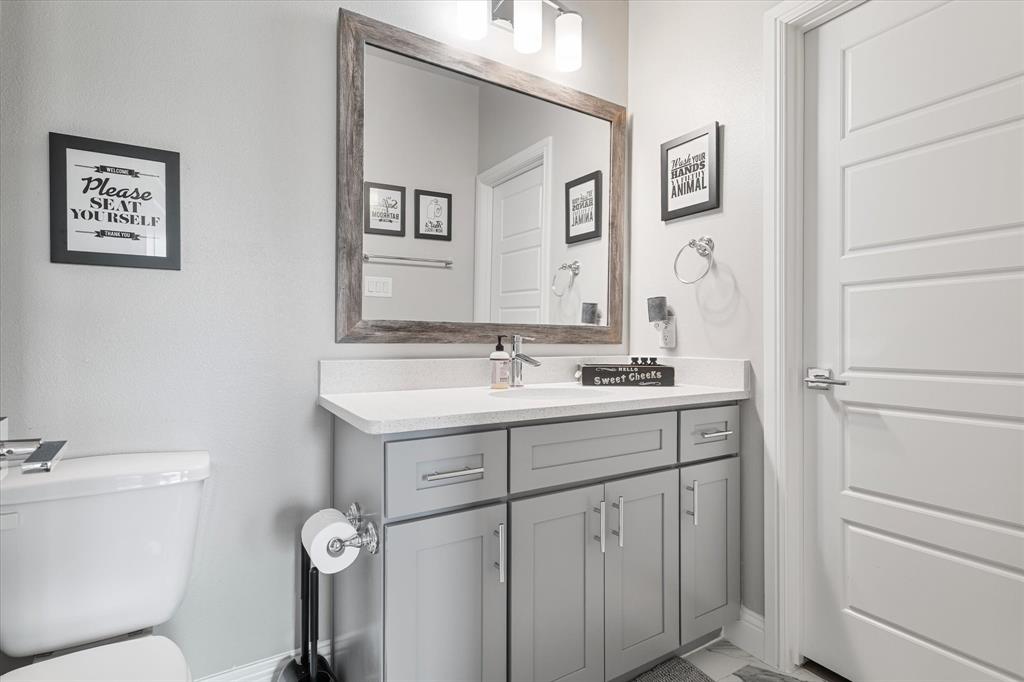 6013 Page Street Frisco, TX 75034 - Photo 34 of 38 a bathroom with a toilet sink and mirror