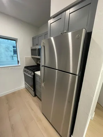 a view of a refrigerator in kitchen and an empty room