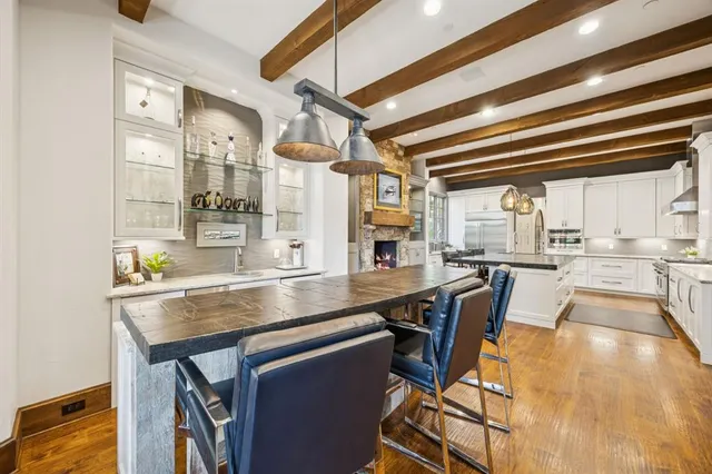 a dining hall with stainless steel appliances granite countertop a table chairs and a view of living room