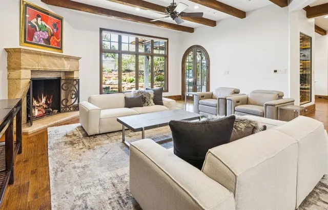a living room with couches a fireplace and a large window with garden view