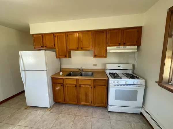 a kitchen with a stove top a refrigerator and a sink