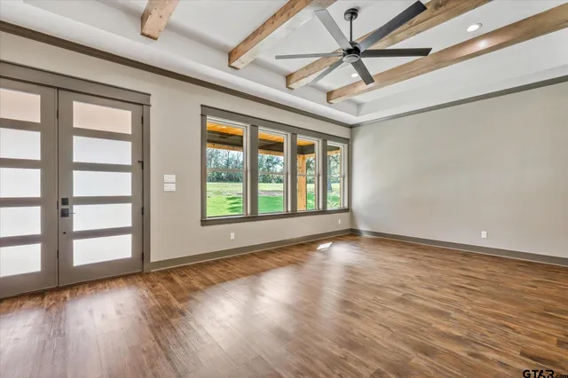 a view of an empty room with a window and wooden floor