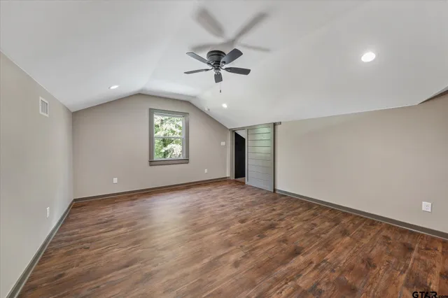 an empty room with windows and ceiling fan