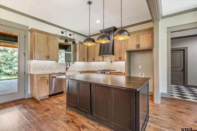 a kitchen with stainless steel appliances granite countertop a sink a stove and a wooden floors