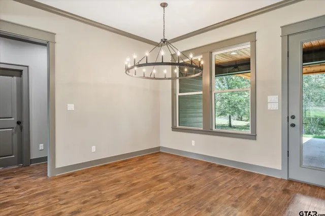 a view of a room with wooden floor chandelier and windows