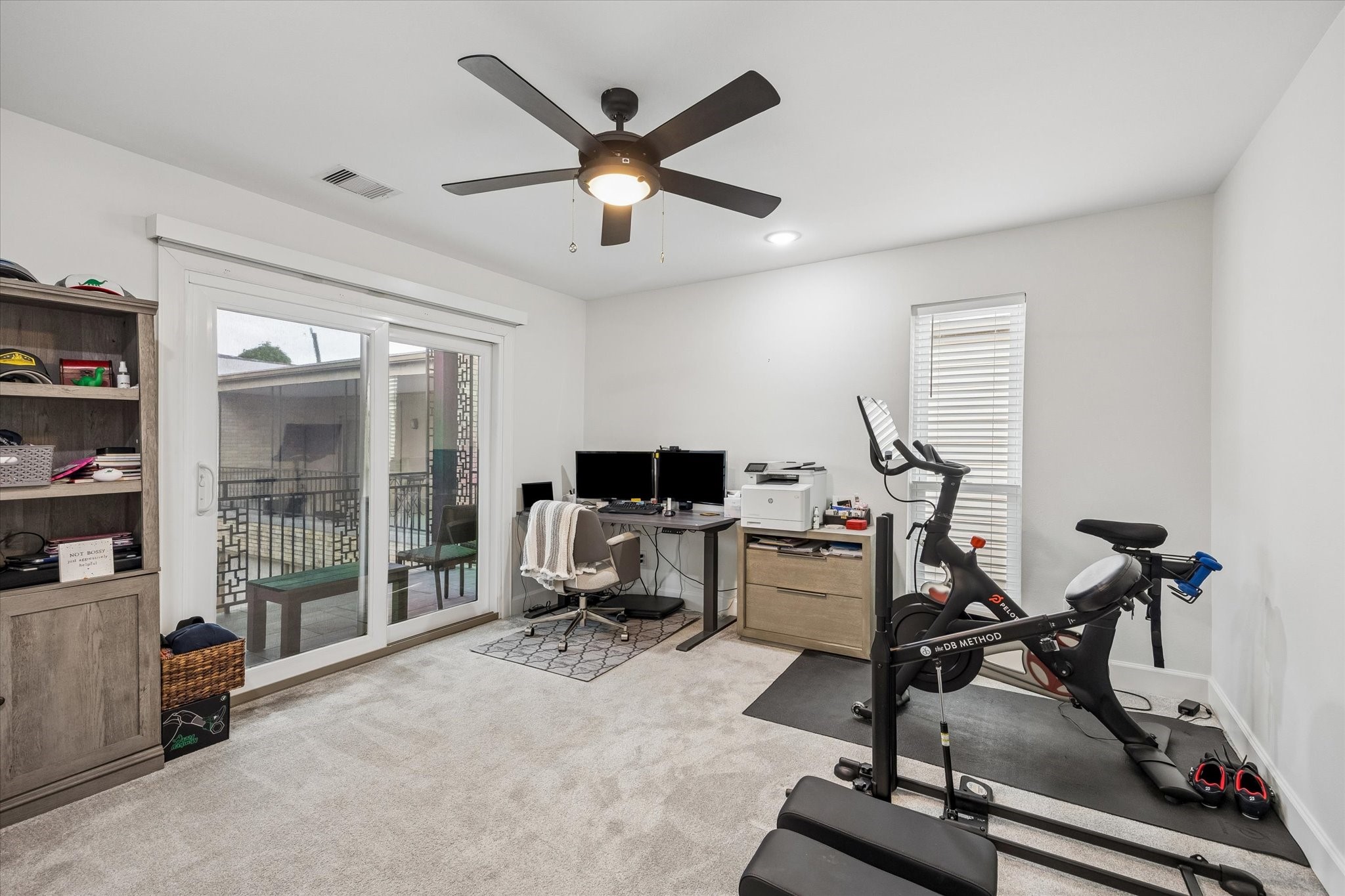 1420 Indiana Street Houston, TX 77006 - Photo 22 of 31 This room features a versatile setup ideal for a home office or gym or as another bedroom. A sliding glass door provides natural light and access to an outdoor space. The neutral decor and carpeted floor create a cozy atmosphere.