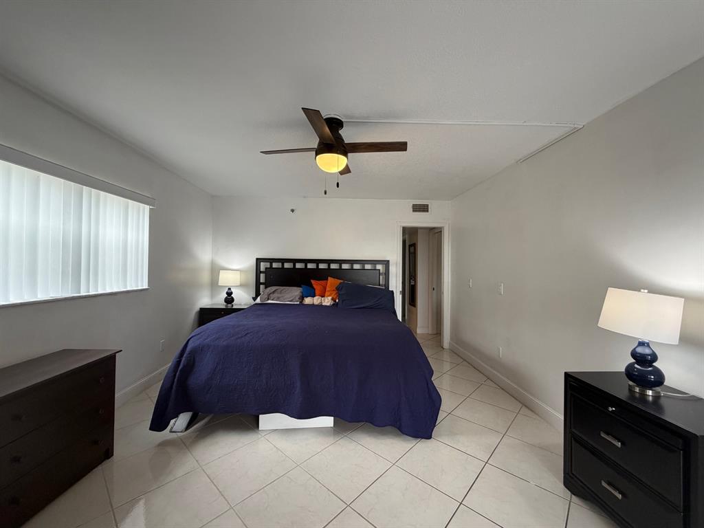 9170 Southwest 14th Street, Unit 4409 Boca Raton, FL 33428 - Photo 16 of 26 a bedroom with a bed and a lamp on the dresser