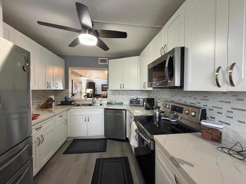 9170 Southwest 14th Street, Unit 4409 Boca Raton, FL 33428 - Photo 9 of 26 a kitchen with a sink stainless steel appliances and cabinets