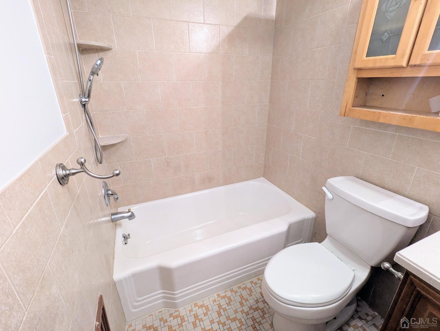 107 Madison Avenue, Unit 2 Dunellen, NJ 08812 - Photo 12 of 18 a white toilet sitting next to a bath tub