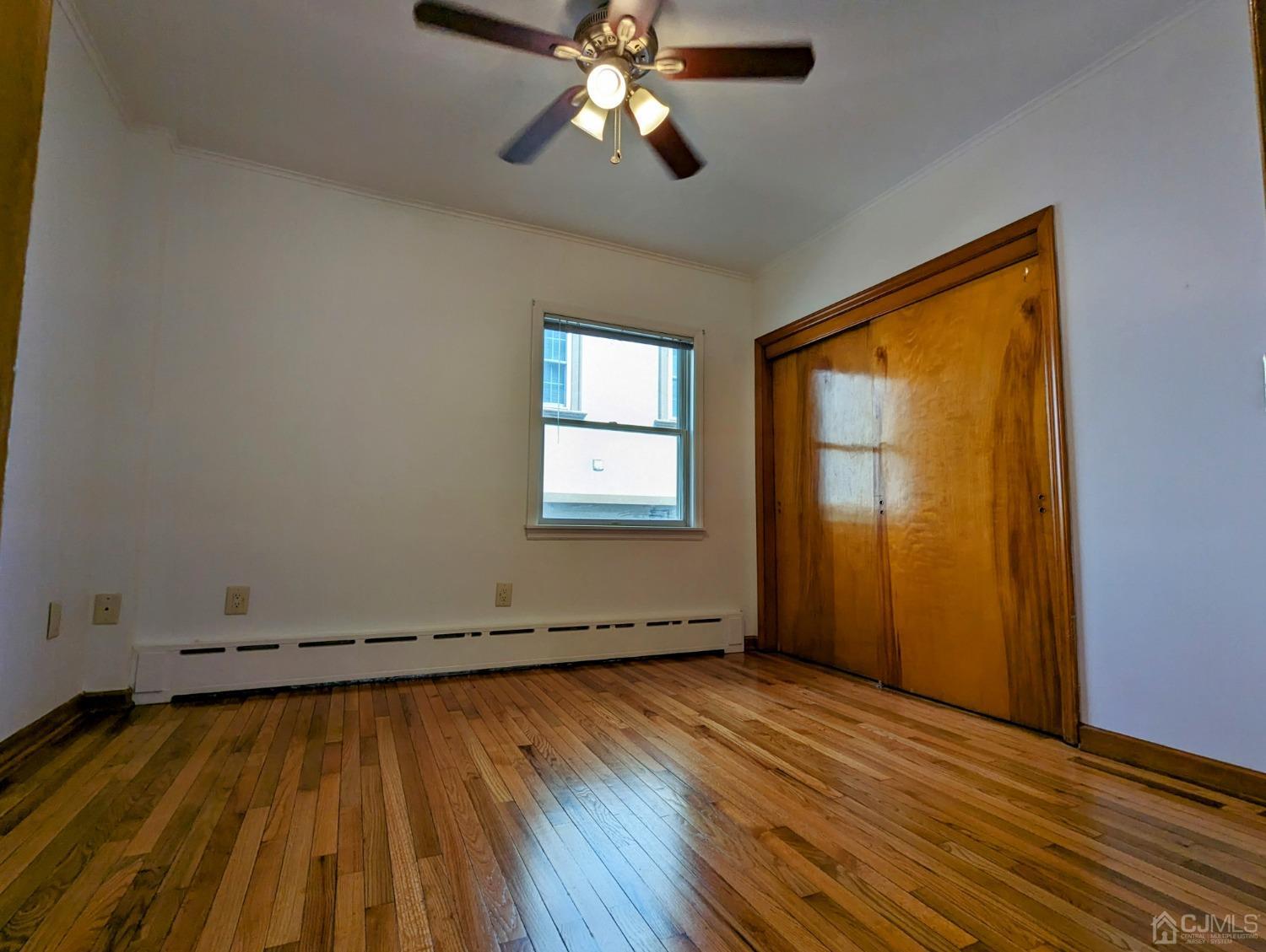 107 Madison Avenue, Unit 2 Dunellen, NJ 08812 - Photo 9 of 18 a view of empty room with wooden floor and fan