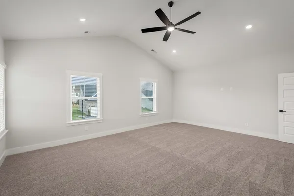 an empty room with ceiling fan and windows