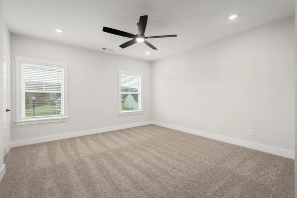 an empty room with windows and fan