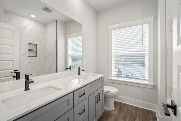 a bathroom with a double vanity sink toilet and a window