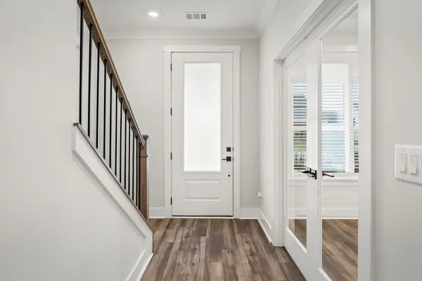 an entryway of a house with wooden floor and stairs