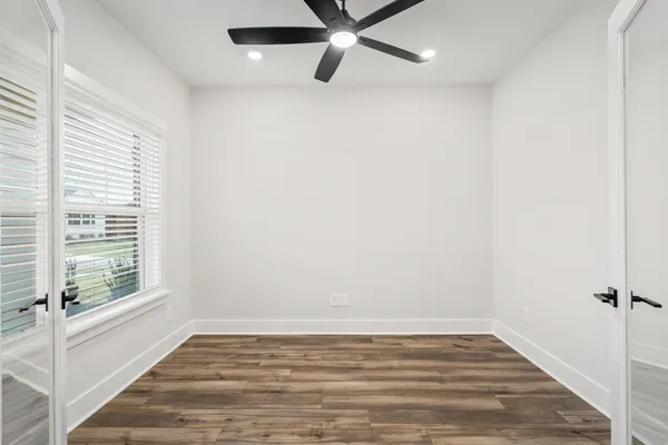 a view of an empty room with wooden floor and a window