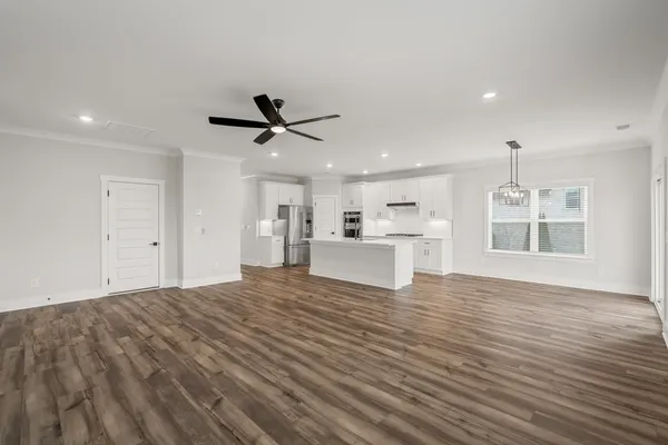 a view of a kitchen with a sink dishwasher refrigerator with white walls and wooden floor