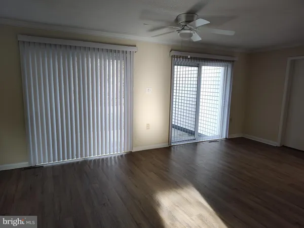 an empty room with wooden floor chandelier fan and windows