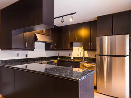 a kitchen with granite countertop a refrigerator a sink and wooden cabinets