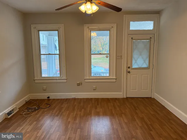 a view of front door with hallway and wooden floor