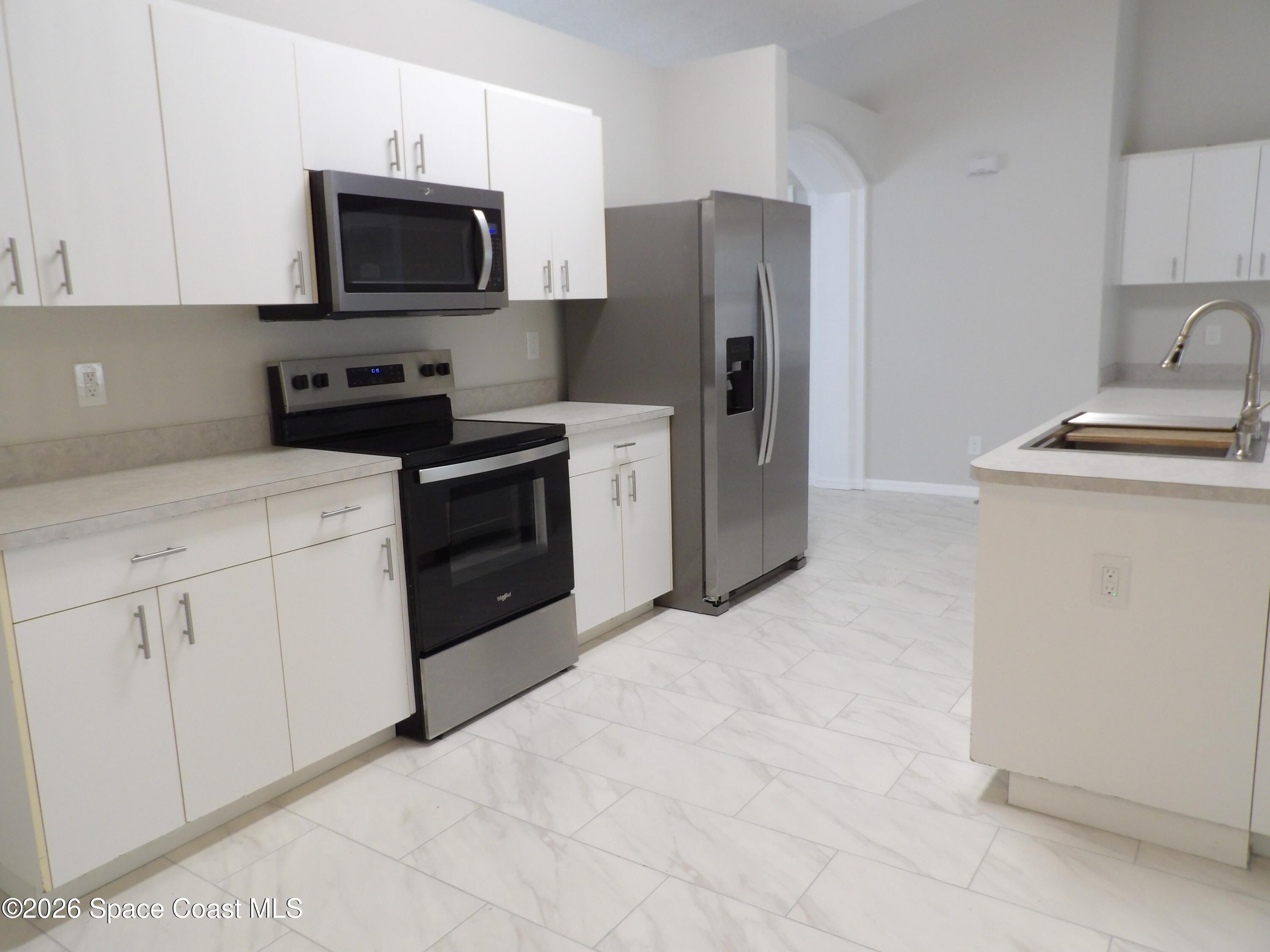 542 Octavius Road Southwest Palm Bay, FL 32908 - Photo 11 of 33 a kitchen with stainless steel appliances a stove microwave and refrigerator