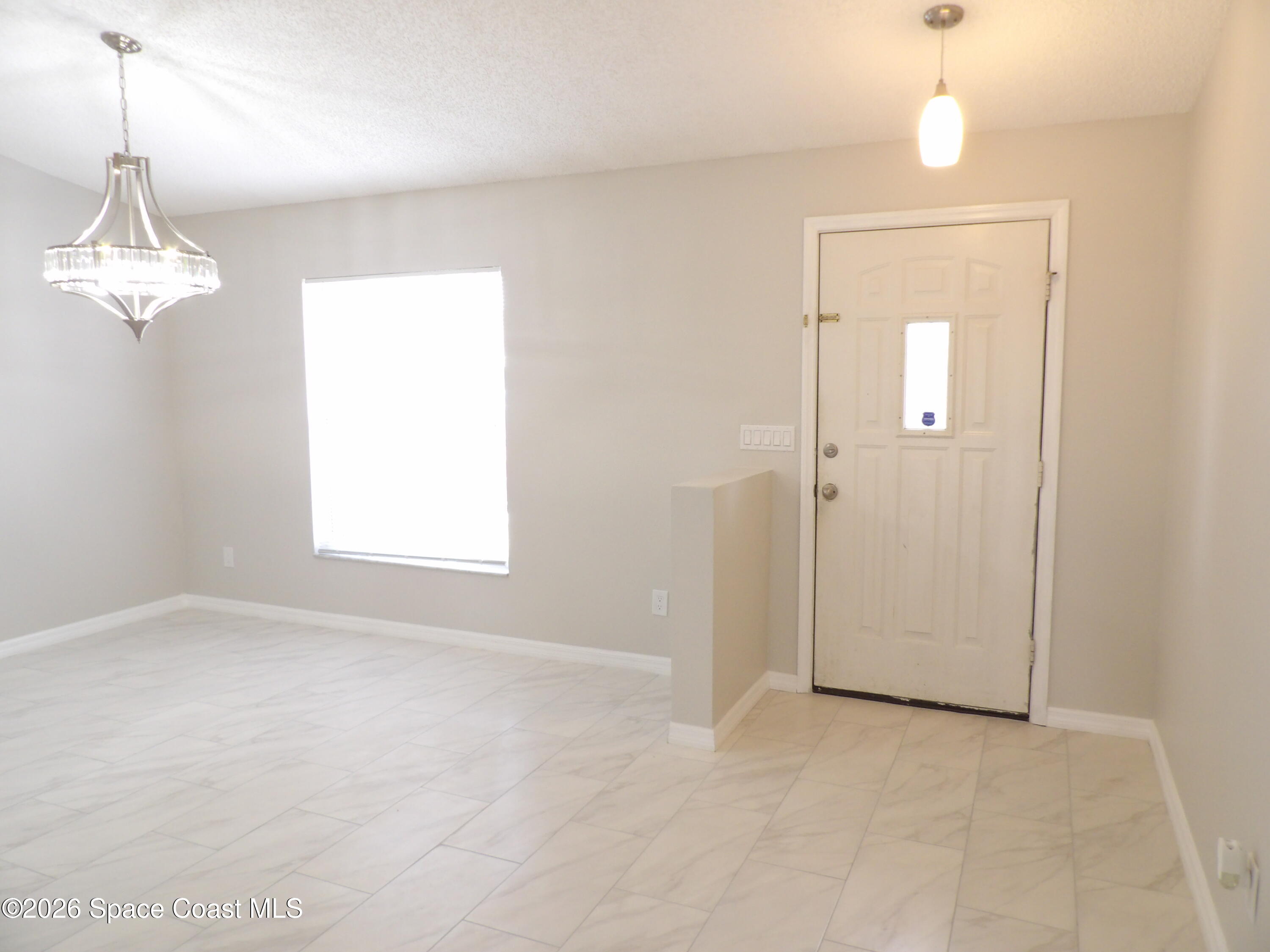 542 Octavius Road Southwest Palm Bay, FL 32908 - Photo 6 of 33 en empty room with windows and chandelier