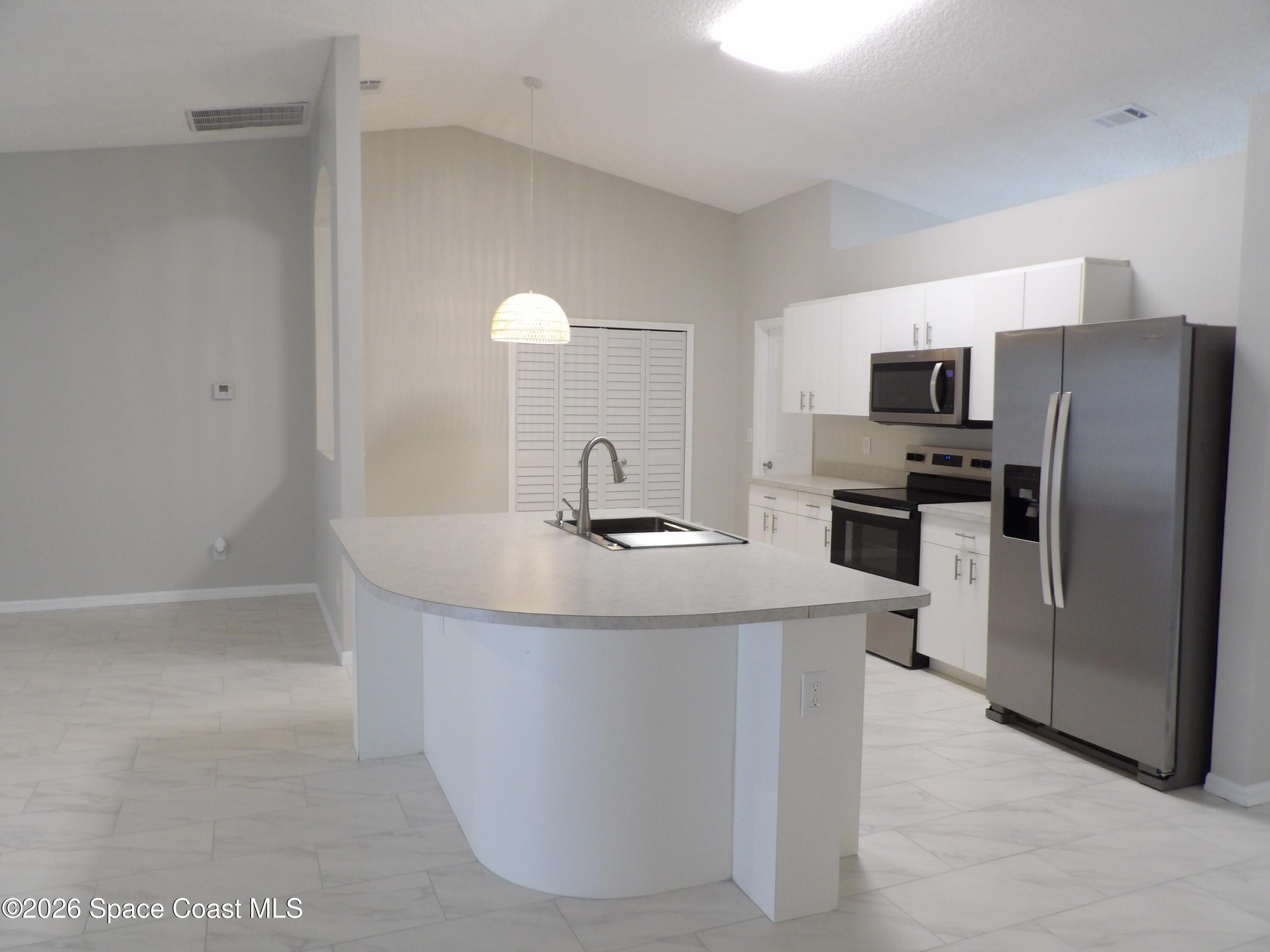 542 Octavius Road Southwest Palm Bay, FL 32908 - Photo 7 of 33 a kitchen with kitchen island a sink stove and refrigerator